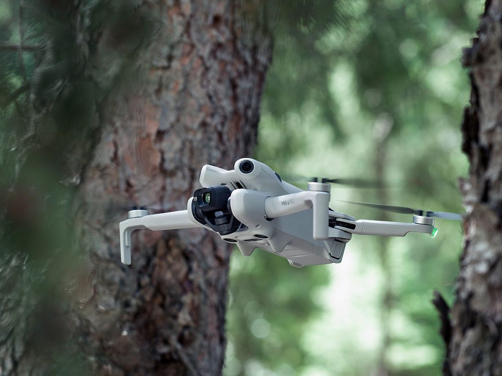 DJI Mini 4 Pro drone flying in the middle of the forest