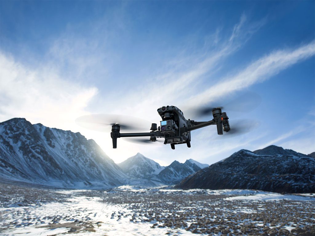 Drone DJI Matrice 30T en vol au milieu des montagnes enneigées