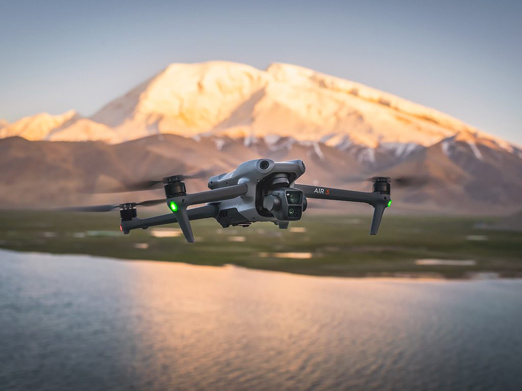 Drone DJI Mavic 3 Air en vol au-dessus d'un lac avec une montagne en arrière-plan
