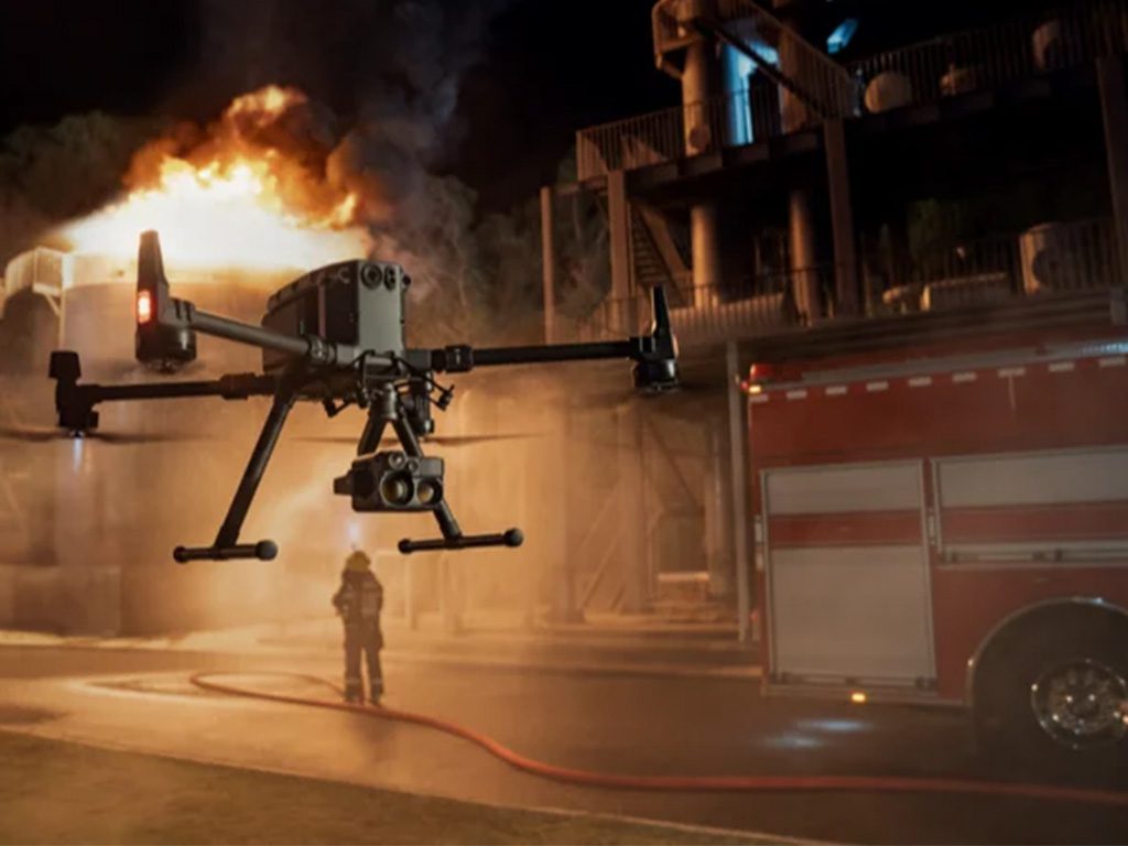 Drone équipé de caméras survole un pompier et un camion de pompiers lors d'un incendie nocturne.