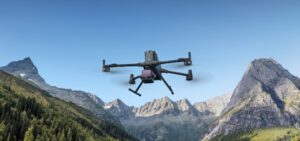Drone professionnel DJI en vol au-dessus d’une vallée montagneuse, équipé d’un capteur LiDAR pour la cartographie aérienne de haute précision